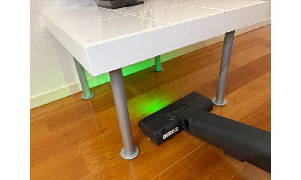 緑色のLEDライトが家具の下のホコリを照らしているところ